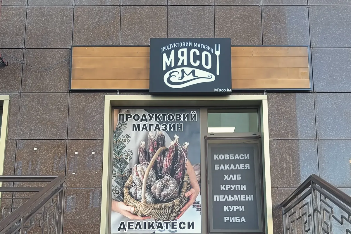 Світловий лайтбокс на дерев'яній основі над входом до магазину